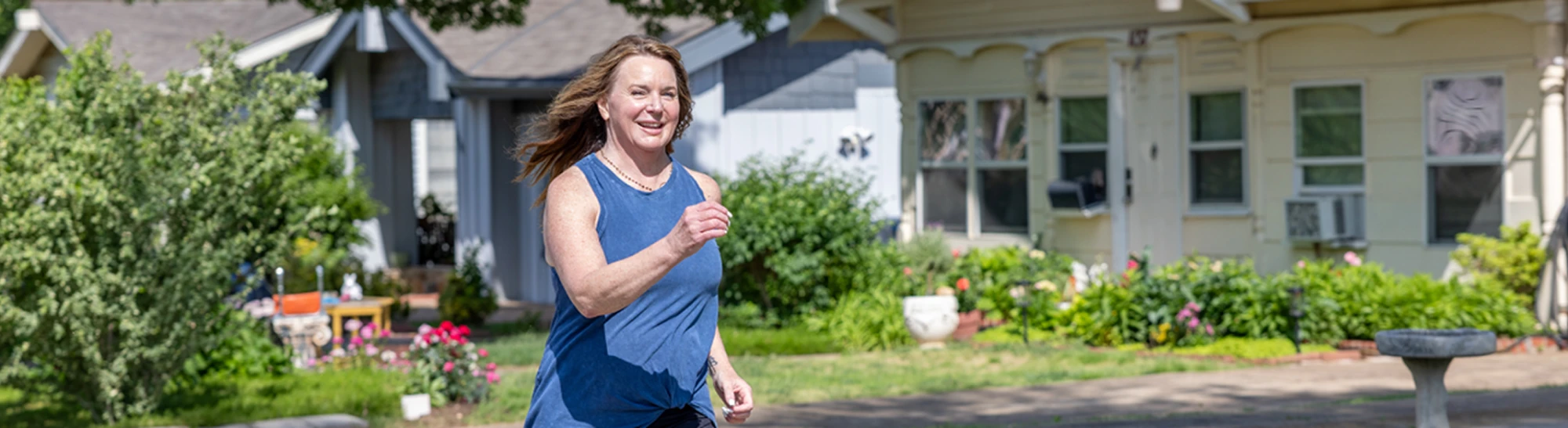 Woman jogging past houses on a sunny neighborhood street