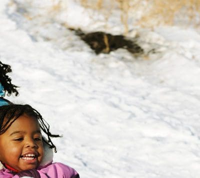 Two girls snow sledding