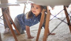 Young girl crawling under table