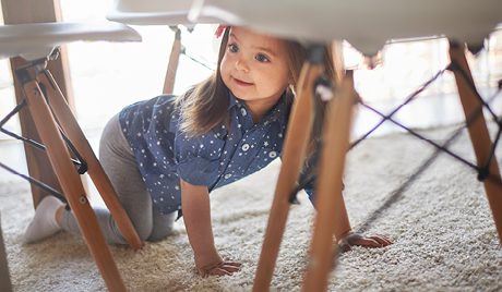 Young girl crawling under table