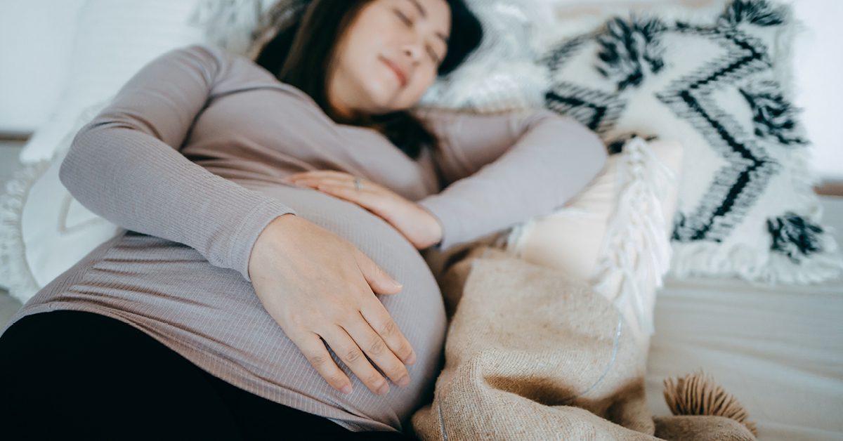 pregnant woman holding stomach while laying down