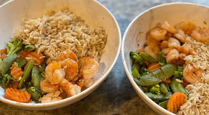 A bowl of rice, shrimp, and veggies.